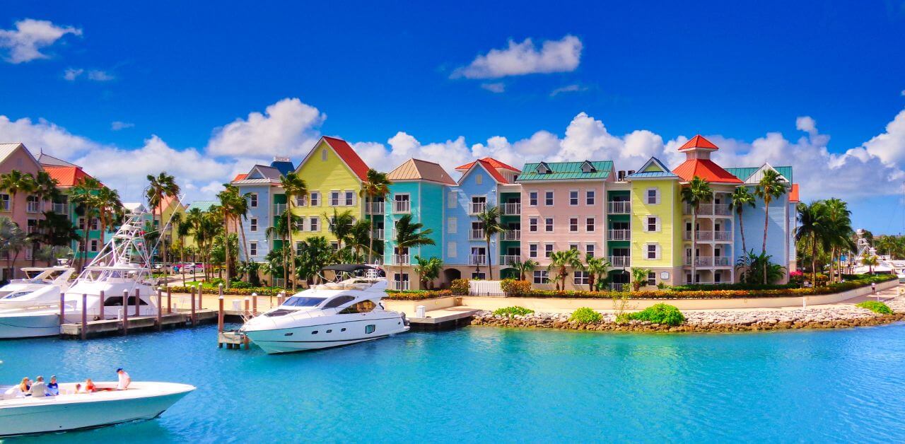alt="Nassau Beach boats and colorful houses Bahamas"
